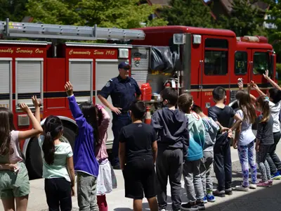 firefighter and fire truck in front of a group of school children