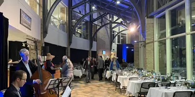 A cellist and a piano player in the foreground with the tables set up to the right