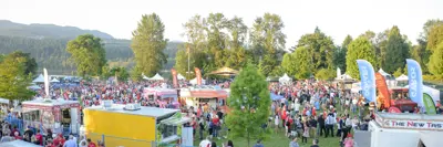 Large crowd of people at Rocky Point Park with food trucks and a stage 