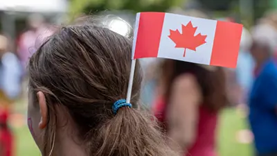 The back of a person's head with a small Canada flag in their hair