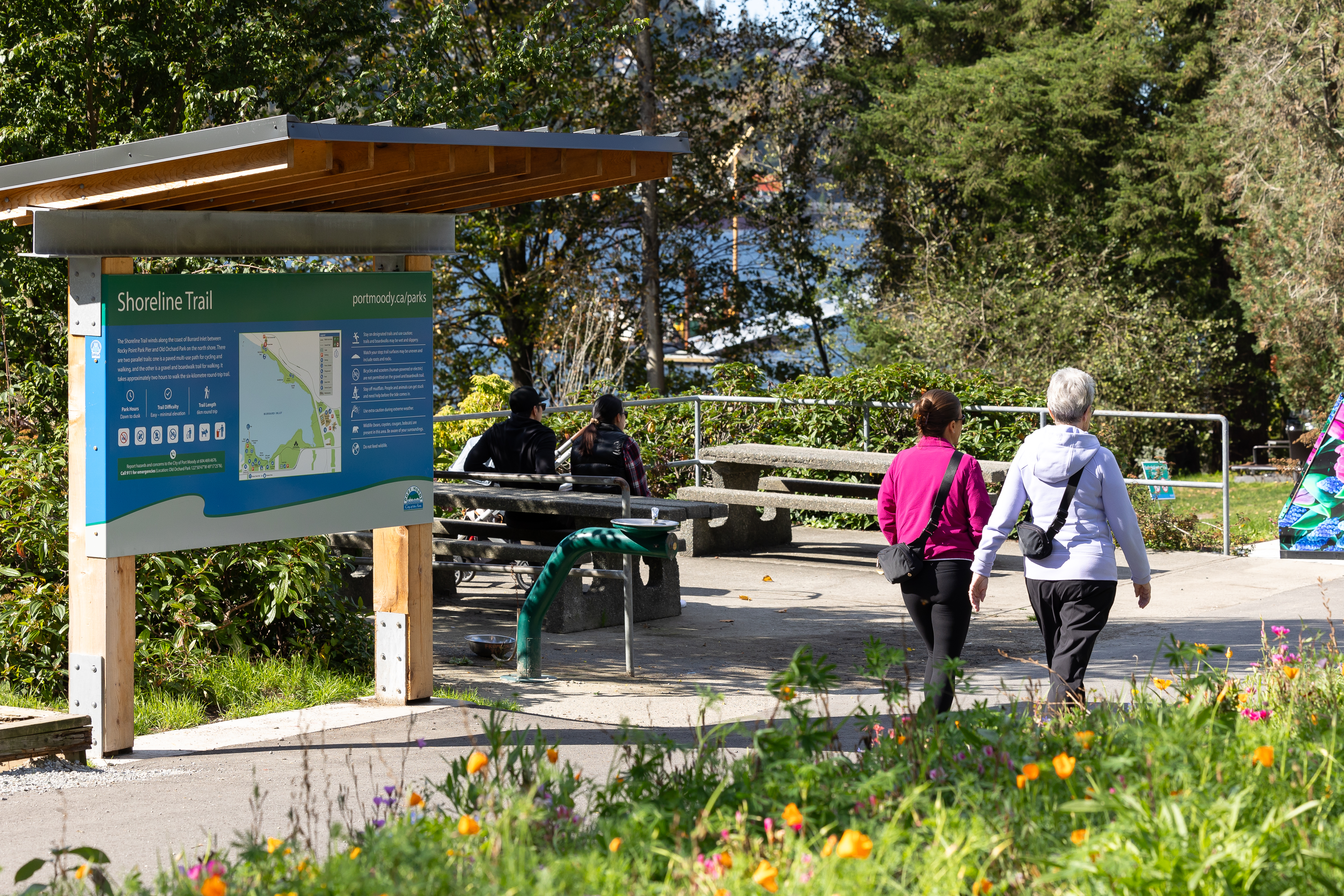People walking along a paved trail, wildflowers in foreground