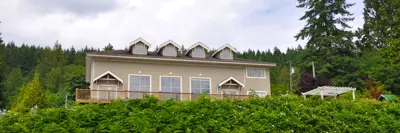 A beige civic facility with a big patio overlooking green bushes