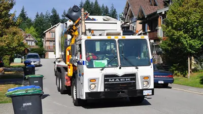 A waste collection truck picking up a garbage cart