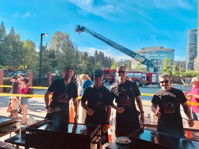 Four off-duty fire fighters in front of a grill