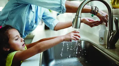 A child washing their hands in the kitcehn sink