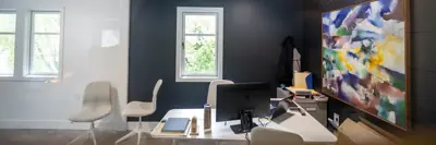 An office with chairs, desk, a computer, and colourful painting
