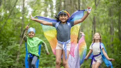 Three children wearing costumes, playing in the woods