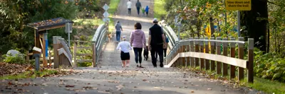 Groups of people walking over a bridge in a park